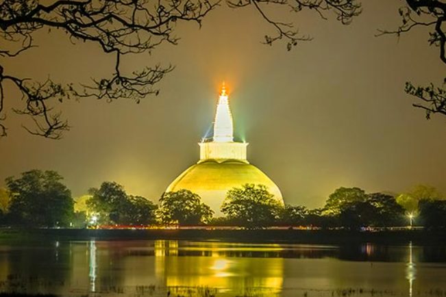 The Ruwanwelisaya dagoba floodlit at night, reflected in the tank below it at Anuradhapura