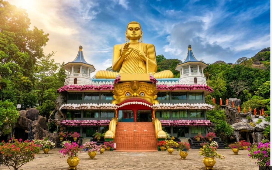 The golden Buddha statue and flower-lined courtyard at the entrance to Dambulla cave temple