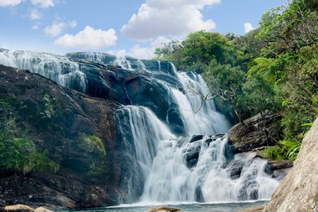Baker’s Falls dropping over dark rock into a pool, surrounded by highland forest near Ella