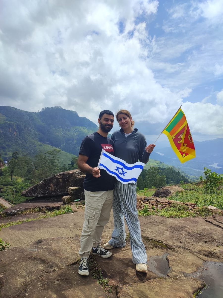 Guests standing on a rock ledge above the tea-covered hills near Ella, holding Sri Lankan and Israeli flags