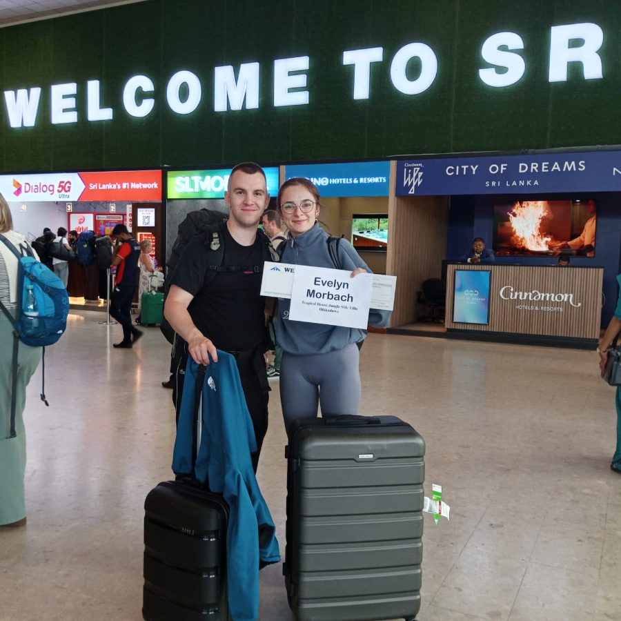 A couple at Colombo airport arrivals holding their welcome board, backpacks and suitcases beside them