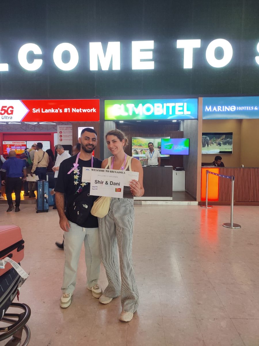 Two guests in the arrivals hall at Colombo airport holding their printed welcome board