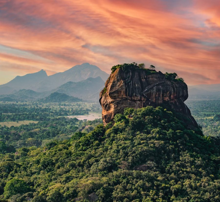 Sigiriya rock fortress rising out of the jungle at sunset, with the hills of the dry zone behind it